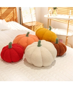 Soft plush pumpkin pillows in assorted colors displayed on a cozy sunlit bedroom bed