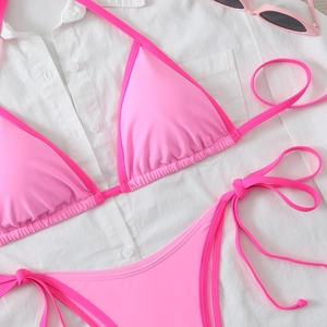 Detailed flat lay of pink tie-side bikini set with sunglasses on white shirt background