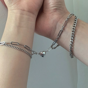 Detailed close-up of silver magnetic heart charm connecting two couples bracelets