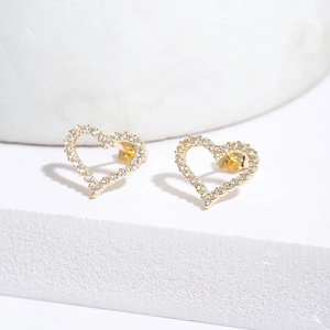 Fashionable gold heart stud earrings with white cubic zirconia pavé on a white pedestal