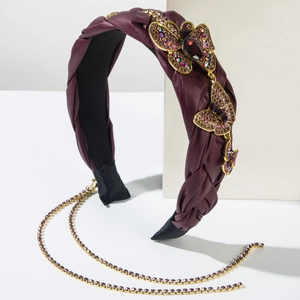 Detail eines gewebten burgunderroten Stirnbands mit goldenen Schmetterlingen und Quasten