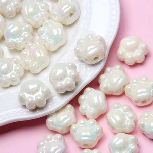 Macro shot of iridescent cat paw acrylic beads for DIY jewelry on a pink background