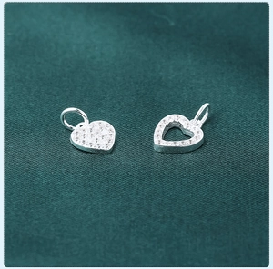 Macro shot of silver heart pendants with pave-set zircons on dark green texture