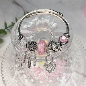 Dettaglio di un bracciale a catena snake argento con acchiappasogni rosa e ciondoli a cuore