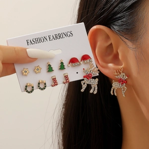 Detail of Christmas earring set with reindeer, tree, and Santa hat studs on model