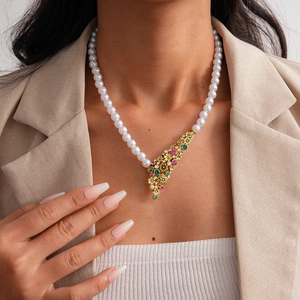 Close-up of vintage flower necklace with white pearls and colorful gemstone pendant