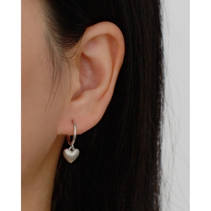 Close-up of s925 silver heart-shaped drop earrings with shell texture on model