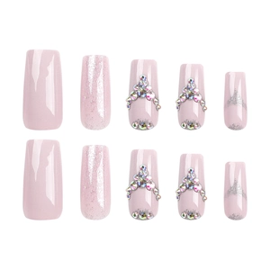 Sparkly long pink press-on nails with glitter accents and rhinestone geometric designs