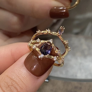 Macro view of gold vine rings set with pear-cut purple zircon and sparkling leaf details