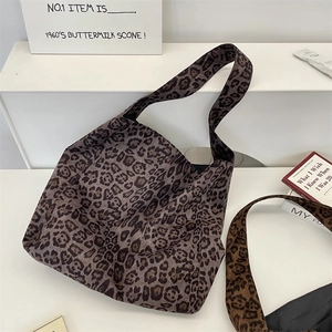 Detailed top view of leopard print canvas hobo tote bags on a white minimalist display stand