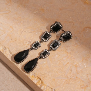 Gros plan de boucles d'oreilles vintage avec pierres noires et micro-diamants argentés