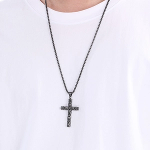 Close-up of a vintage dark grey stainless steel cross pendant with box chain on a model