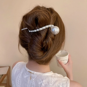 Detail of elegant pearl hair pin in a French twist updo with silver metal and white pearls