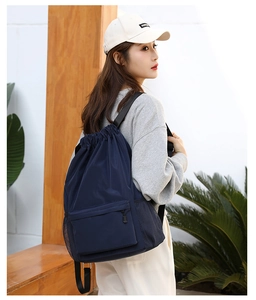 Lightweight drawstring backpack detail view, featuring front zipper pocket and mesh side pockets.