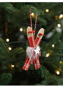 Detail of red wooden sleigh ornament with white star hanging on Christmas tree branch