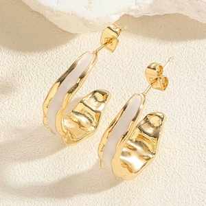 Detailed macro view of vintage gold crescent earrings with white enamel and hammered texture
