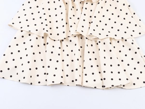 Gros plan sur la robe à volants étagés beige à pois noirs montrant la texture légère