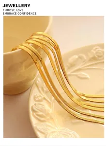 Detailed view of layered gold blade snake chains styled with elegant ceramic tableware