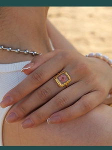Close-up of a gold square ring with pink dried flowers on a model's hand