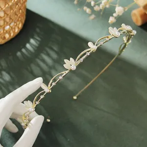 Close-up of golden leaf headband with delicate pearls and white floral petal details