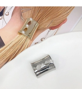 Detail of gold and silver U-shaped metal hairpins with pearl accents for ponytails