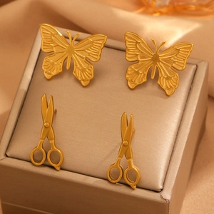 Vue détaillée de boucles d'oreilles papillon et ciseaux dorés sur un coffret à bijoux