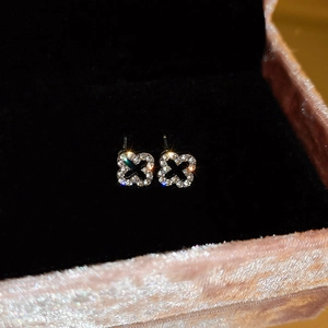 Close-up of diamond-studded gold flower stud earrings in a pink velvet jewelry box