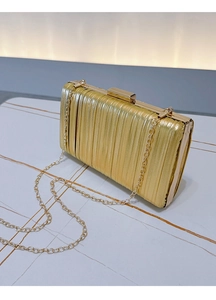 Detail of elegant pleated gold evening clutch with sleek metallic chain strap