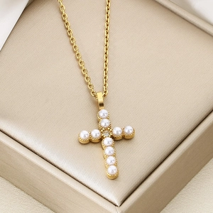 Detailed close-up of a gold cross pendant featuring elegant white pearls and zircon accents