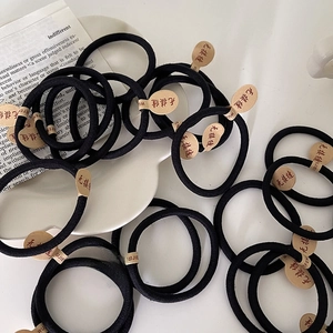 Détail d'élastiques à cheveux noirs sans couture avec étiquettes rondes en papier kraft