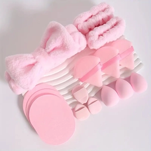 Pink beauty set including plush headband, wristbands and various makeup sponges on white background