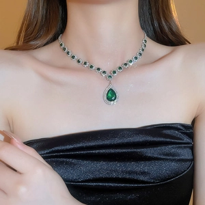 Macro shot of silver necklace with pear-cut green gemstone and teardrop pendant
