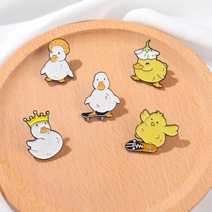 Close-up of five cartoon duck and chick enamel pins on a circular wooden display tray