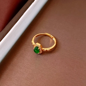 Detailed close-up of a vintage gold ring with an oval green stone and zircon halo