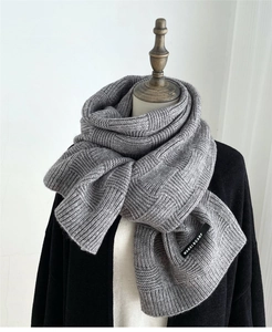 Close-up of gray checkered knit scarf texture with a small woven brand label detail