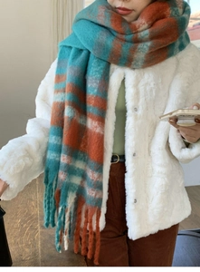 Close-up of soft plaid scarf with blue, orange, and white tassels and fluffy mohair texture