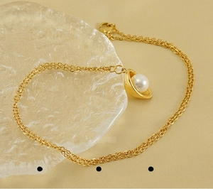 Close-up of 18k gold plated stainless steel necklace featuring a shell pendant with pearl