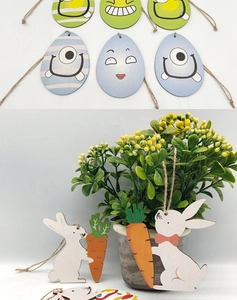 Close-up of wooden Easter egg monsters and white bunnies with carrots hanging on jute twine