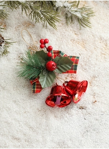 Close-up of red metal bells with pine needles, berries and plaid ribbon on snow
