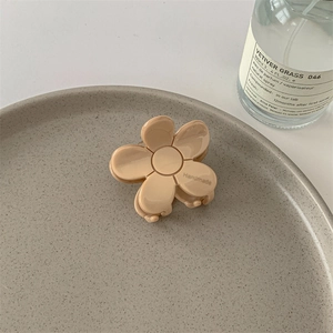 Détail d'une pince à cheveux fleur avec texte Handmade sur plateau céramique et parfum
