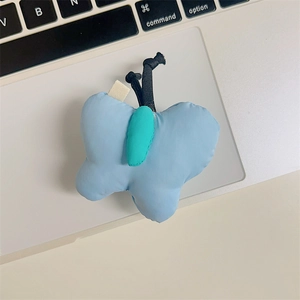 Macro shot of blue butterfly plush phone stand resting on a sleek laptop keyboard