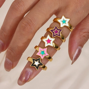 Close-up of five colorful star enamel rings with gold finish on hand in detail