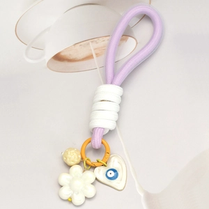 Détail du porte-clés tressé violet avec fleur blanche et breloque cœur mauvais œil