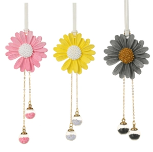 Detailed view of handmade daisy car charms in pink, yellow, and grey with crystal accents