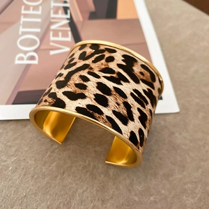Detail view of wide leopard print cuff bracelet with matte gold metallic inner finish