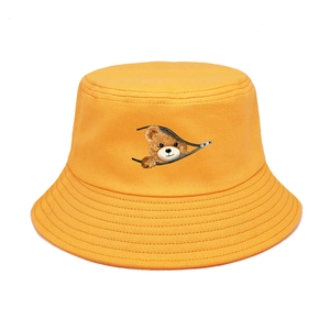 Detail of bright yellow bucket hat featuring a creative cartoon bear zipper print