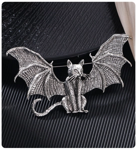 Detailed close-up of gothic silver winged cat brooch showing intricate metal wing textures