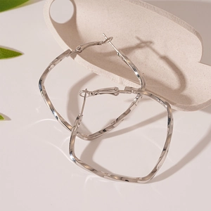 Detail of twisted square geometric earrings with polished silver finish and needle clasp