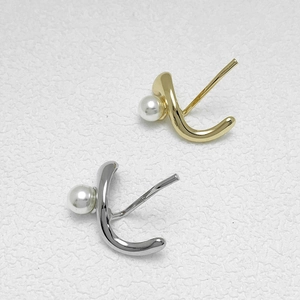 Elegant gold and silver S-curve pearl stud earrings set against a textured background