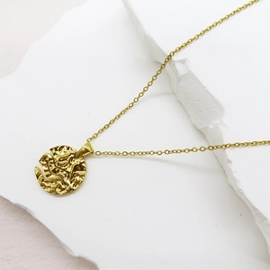 Macro detail of golden hammered texture round pendant on a fine necklace chain